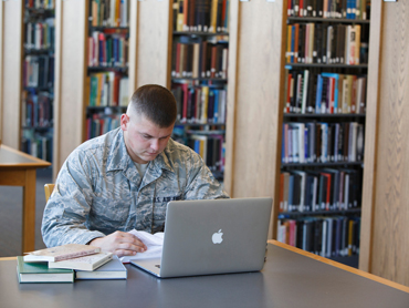 Military student working on a laptop in the library