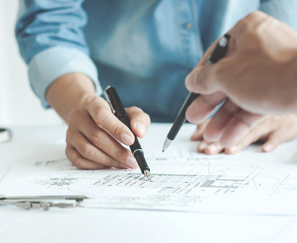 People holding pens and reviewing architectural plans