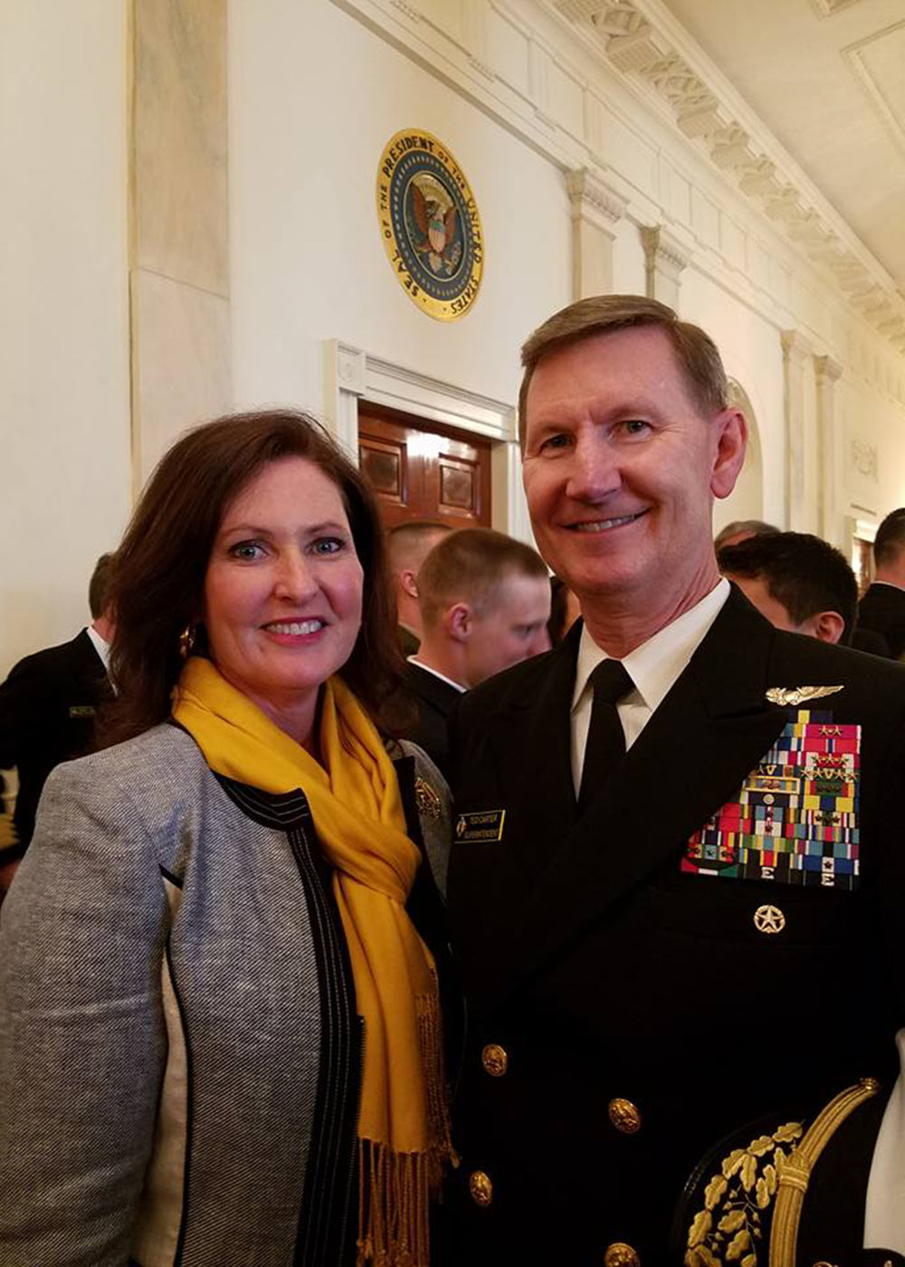 Photo of Lynda and Ted Carter in the White House with a presidential seal in the background