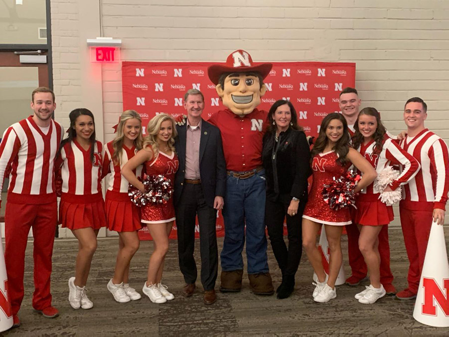 Lynda and Ted Carter pose with Herbie Husker, cheerleaders and Scarlets