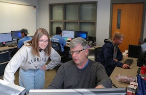  Benson works with a student in UNK's Supply Chain Center. Students can use workspaces and equipment to participate in virtual internships during the academic year