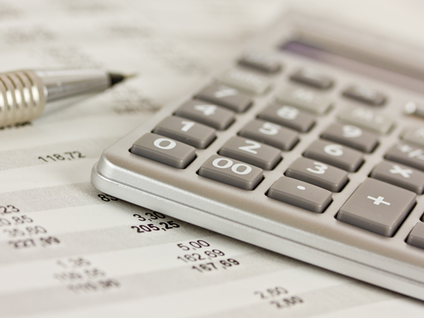calculator and pen laying on accounting spreadsheet