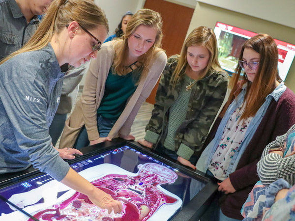 students gathered around a digital medical learning device